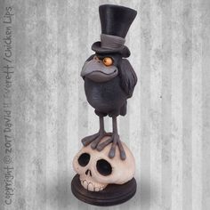 a statue of a bird with a top hat on it's head sitting on a skull