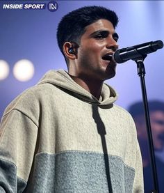 a man standing in front of a microphone with his mouth open and wearing a hoodie