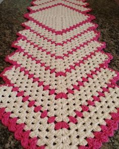 a crocheted table runner with pink and white trim