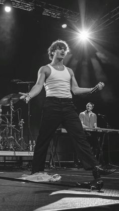 a man standing on top of a skateboard in front of a microphone and drums