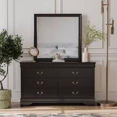 a bedroom with a dresser, mirror and potted plant on the floor in front of it