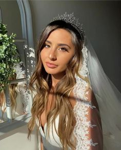 a woman in a wedding dress is posing for the camera with her veil draped over her head