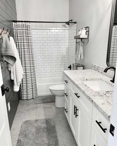 An easy way to add subtle texture to a cool-toned bathroom is through a shiplap wall. If you're feeling creative, consider dark gray paint over the wood panels to create a more prominent accent wall. The tub-shower combo is surrounded by subway tile, and a light gray paint decorates the wall opposite the shiplap with a white and granite vanity...   Image: hickorynutfarmbarndominium