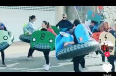 several people in costumes are carrying large tires