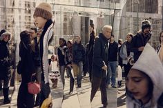 a group of people walking down a street next to tall buildings with glass walls on each side