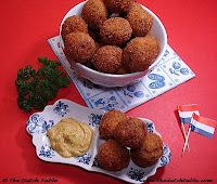 there is a bowl full of fried food and dipping sauce on the plate next to it