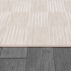 an area rug with wood flooring and white stripes on the top, in grey tones