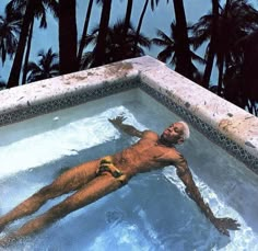 a man swimming in a pool surrounded by palm trees