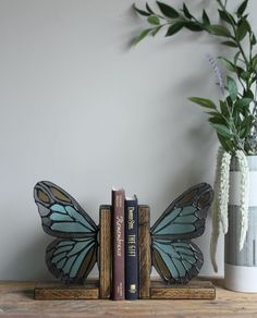 two books are sitting on a shelf next to a vase with flowers and a butterfly