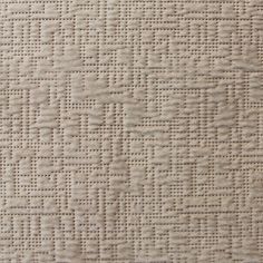 an upholstered fabric textured with small squares and dots in neutral tones,