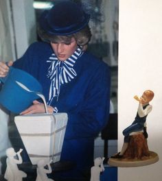 a woman in blue coat and hat next to figurines