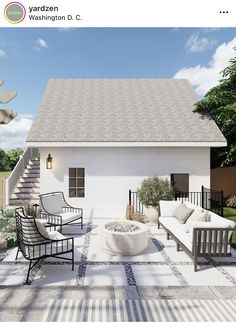 a white house with some chairs and a table in front of it on a sunny day