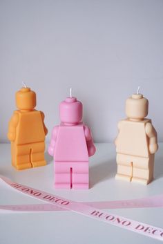 three legos are sitting next to each other on a table with a pink ribbon