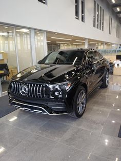 a black mercedes suv parked in a showroom