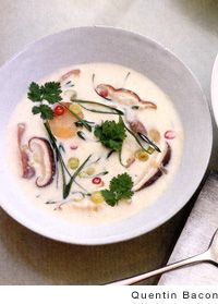 two bowls of soup are sitting next to each other with spoons and utensils