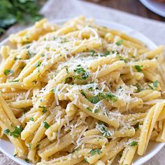 a white plate topped with pasta and parmesan cheese on top of a table