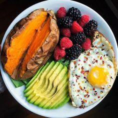 a white plate topped with eggs, fruit and bread next to a cup of coffee