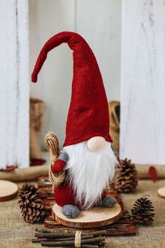 a red and white gnome figurine sitting on top of a piece of wood