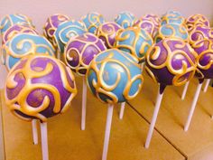 there are many cake pops with different designs on top of each other in blue, purple and yellow