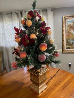 a christmas tree with fruit on it sitting on top of a wooden table