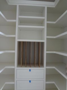 an empty white bookcase with some blue tape on the bottom shelf and two drawers