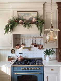 a blue stove top oven sitting in a kitchen next to a wall mounted pot rack