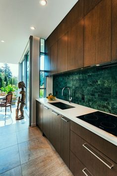 a modern kitchen with wood cabinets and marble counter tops, along with an outdoor dining area