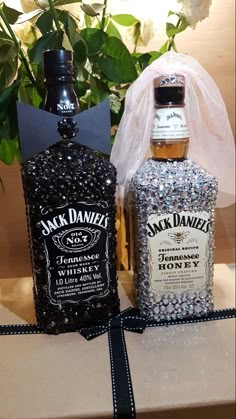 two bottles of jack daniels are sitting next to each other on a table with flowers in the background