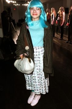 a woman with blue hair is standing in a room