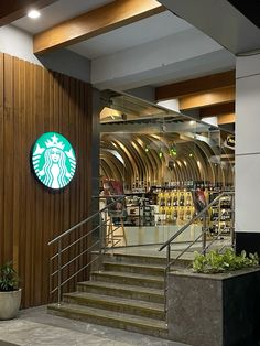 a starbucks coffee shop with stairs leading up to the counter and planters on either side