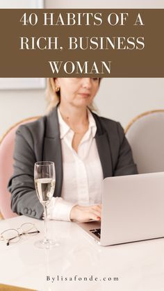 a woman sitting at a table with a laptop and wine glass in front of her