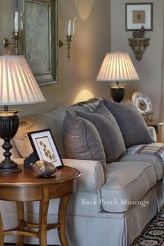 a living room with couches, lamps and pictures on the table in front of them