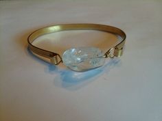 a gold bracelet with a white stone on it