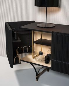 a black cabinet with a lamp on top and some items in the bottom shelf next to it