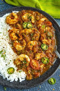 a black plate topped with rice and shrimp next to a green towel on top of a blue surface