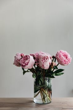 pink flowers in a clear vase on a wooden table