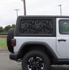 a white jeep parked in a parking lot with skulls on it's back window