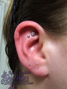 a close up of a person's ear with two piercings on it,