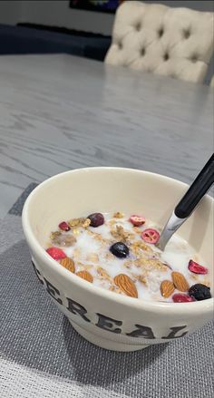 a bowl of cereal with yogurt and fruit in it sitting on a table