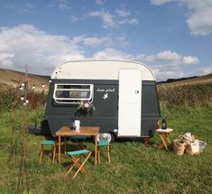 an rv is parked in the middle of a field with picnic tables and chairs around it