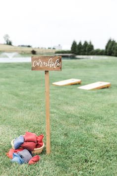 a sign that says cornhole next to a basket filled with stuffed animals on the grass