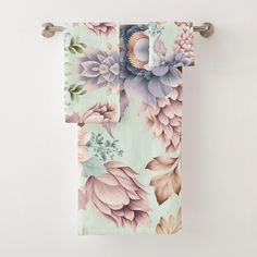 a towel hanging on the wall with flowers and leaves in pastel colors, next to a toilet paper roll