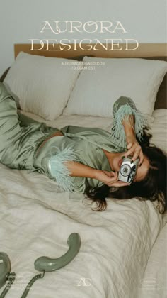 a woman laying on top of a bed holding a camera