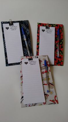 three notepads with writing on them are next to a pen and clipboard