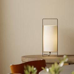 a table lamp sitting on top of a wooden table next to a potted plant