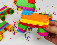 a person is holding a small toy made out of construction paper and streamers on the floor