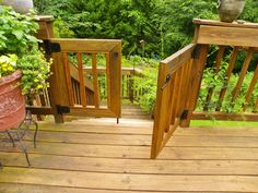 two wooden gates open on a deck with potted plants in the foreground and trees in the background