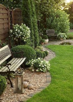 a wooden bench sitting in the middle of a lush green yard next to a fence