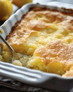 a close up of a casserole in a pan with a spoon and lemons behind it