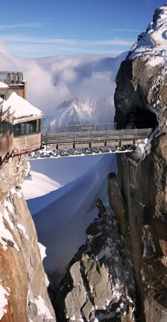 a train traveling over a bridge on top of a snow covered mountain in the mountains